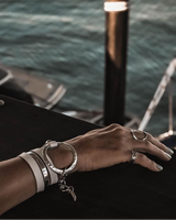 Hand with multiple bracelets on a boat against a water background