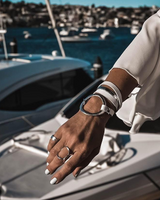 Hand with bracelets and rings on a boat with a cityscape in the background