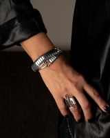 Polished silver hematite wrap bracelet on a wrist, featuring layered design, curved metal bars, and an adjustable fit.