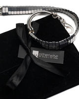 Silver hematite wrap bracelet with polished beads, curved metal bars, and an adjustable fit, presented against a black suede pouch.