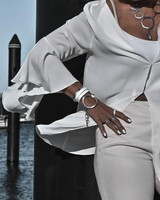 Person wearing a white outfit with accessories by a waterfront