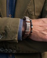 Close-up of a person wearing a bracelet with a green jacket and blue shirt.