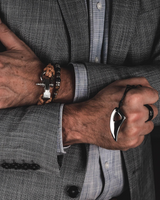 Close-up of a person wearing a bracelet and a ring with a suit jacket.