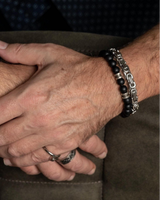 Close-up of two hands clasped together with a watch and bracelet on a dark background