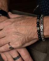 Close-up of a person's hands with bracelets and rings on a neutral background