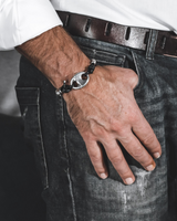 Person wearing a bracelet with a visible brand logo, sitting on a couch.