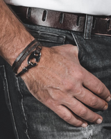 Hand wearing a bracelet with a belt and jeans in the background