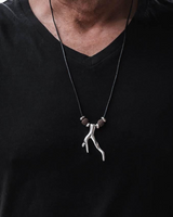 Person wearing a black shirt with a necklace featuring a unique pendant.