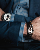 Close-up of a person wearing a watch and bracelets with a suit jacket.