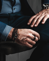 Close-up of a person's hands with jewelry on a dark background