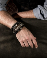 Person wearing multiple bracelets on a wooden surface