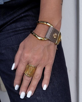Hand wearing a gold ring and bracelet on a dark background