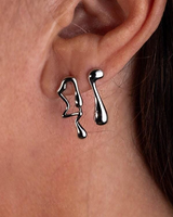 Silver earrings worn on an ear with a close-up view of the jewelry.