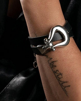Black leather bracelet with a silver clasp on a wrist against a dark background