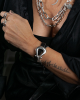 Person wearing silver chain jewelry and a black shirt with visible tattoos.