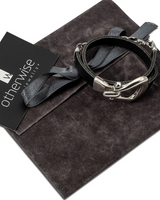 Bracelet with silver clasp on a dark fabric surface with 'otherwise' jewelry card.