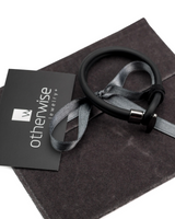 Black bracelet on a gray fabric with 'otherwise jewelry' card