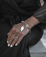 Close-up of a person's hand wearing silver bracelets and rings on a blurred background