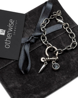Silver bracelet with charms on a black box with 'otherwise jewelry' card