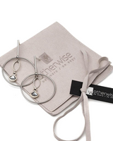 Elegant silver hoop earrings featuring a dangling Austrian crystal pendant in "Silver Night," displayed on a soft suede pouch.