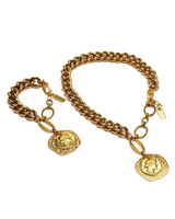 Gold chain bracelet with two round pendants on a white background