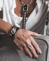 Black leather wrap bracelet featuring a funky silver clasp, styled with a layered necklace and a silver ring.