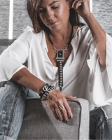 Black leather wrap bracelet with a funky silver clasp, worn by a model with a white top and distressed jeans.