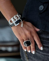 Hand wearing a silver bracelet and black ring with a blurred background