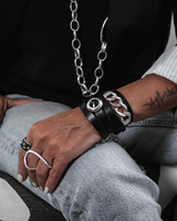 Person wearing multiple bracelets and rings on their wrist and hand.