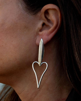 Silver heart-shaped earring worn by a person with brown hair.