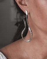 Silver hoop earring worn by a person with a neutral background
