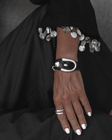 Hand wearing a bracelet and ring with a black background