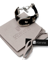 Black and silver bracelet on a gray cloth with 'otherwise' branding.