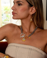 Woman wearing gold jewelry including a necklace, earrings, and bracelets.