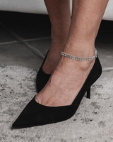 Dainty 999 silver antique plated anklet with round charms, worn on an ankle, paired with black high-heeled shoes.