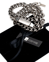 Bold convertible triple-wrap chain in stainless steel with a chunky curb design, resting on a black suede pouch.