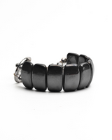 A black beaded bracelet with glossy, rounded rectangular beads and a silver-toned metal clasp, shown on a plain white background.
