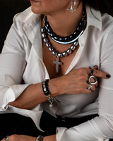 Person wearing multiple necklaces, bracelets, and rings with a white shirt.