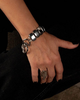 Hand wearing a silver bracelet with a dark background