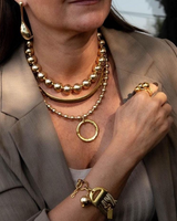 Woman wearing gold jewelry including a necklace, bracelet, and earrings.