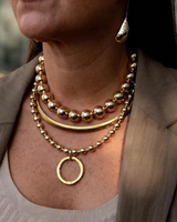Close-up of a person wearing multiple gold necklaces and earrings.