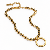 A gold-toned beaded necklace featuring a large textured circular ring pendant, displayed on a clean white background.