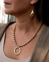 Close-up of a woman wearing a gold necklace and earring.