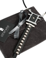 Necklace with black leather strap and silver beads on a gray surface, branded 'otherwise jewelry'.