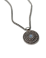 Layered metal necklace featuring a twisted chain and a circular pendant with a blue stone in the center.