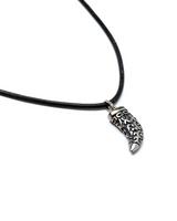 Layered leather and metal necklace set featuring a black leather cord and an ornate stainless steel tooth pendant.
