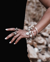 Chunky silver-plated iron ball snake chain cuff bracelet worn on the wrist, layered with additional bracelets.