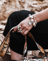 Chunky silver-plated iron ball snake chain cuff bracelet worn on wrist, paired with matching rings, with a contrasting handbag.