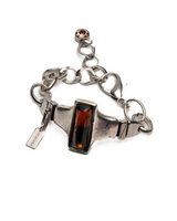 Chunky silver-plated bracelet featuring an Indian red crystal centerpiece, leather details, and a unique clasp design.
