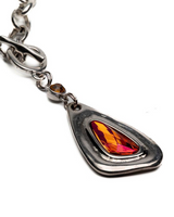 Chunky silver-plated necklace featuring a large red Austrian crystal pendant, with an irregular T-clasp and antique chain.